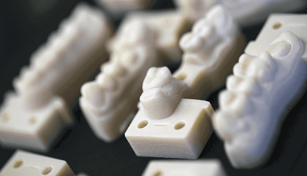 A prototype of a 3D printed teeth kept on a black tile.