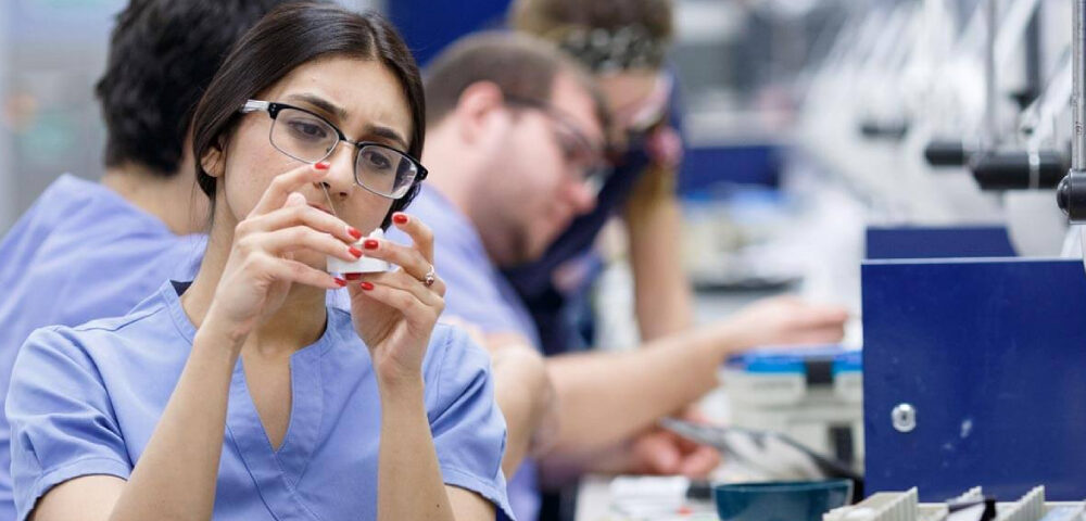 A dentist is experimenting with dental material along with her colleagues at the lab.