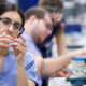 A dentist is experimenting with dental material along with her colleagues at the lab.