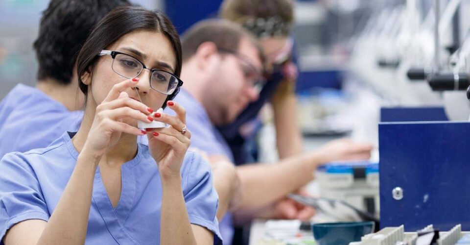 A dentist is experimenting with dental material along with her colleagues at the lab.