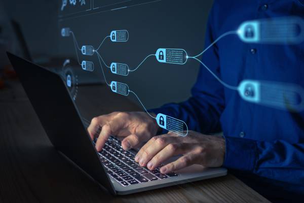 View of a man working on his laptop where an imaginary image of the block chain technology is displayed in front of him.